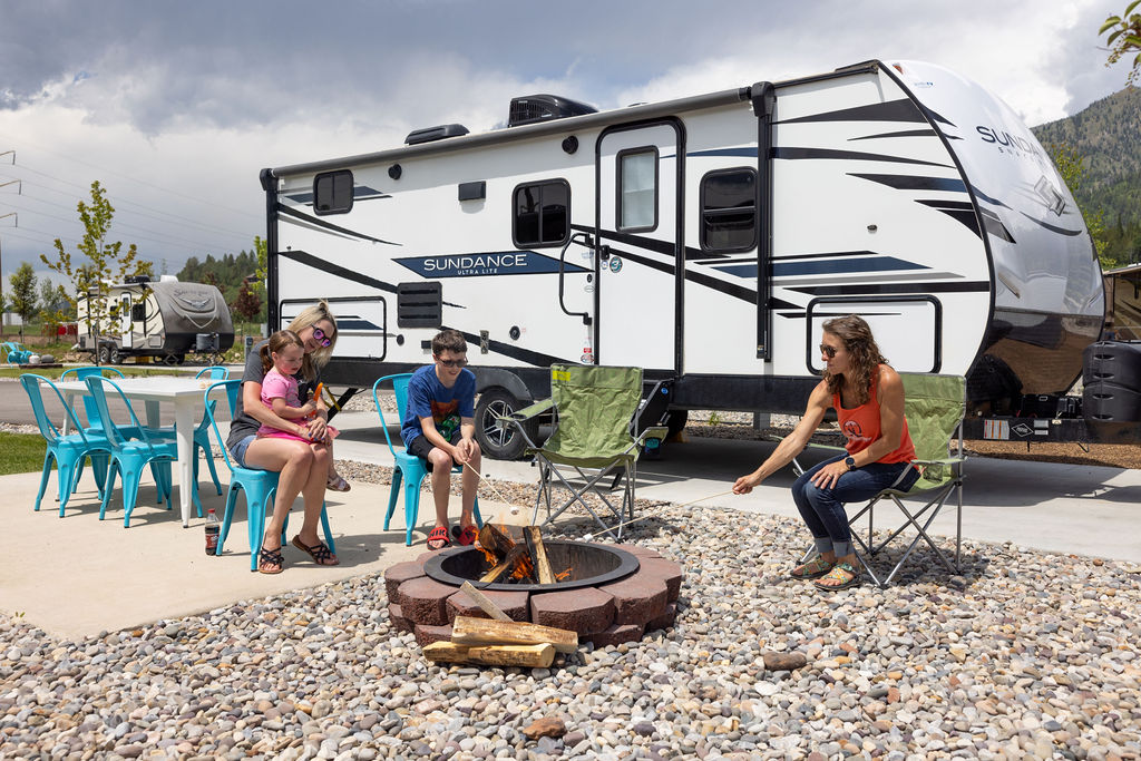 A family of four roasts marshmallows over a campfire at their RV site.