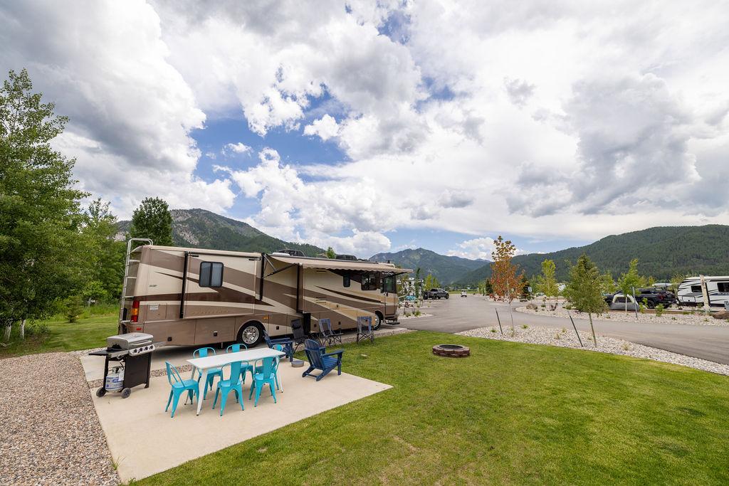 A back-in RV campsite with a large lawn and picnic area.